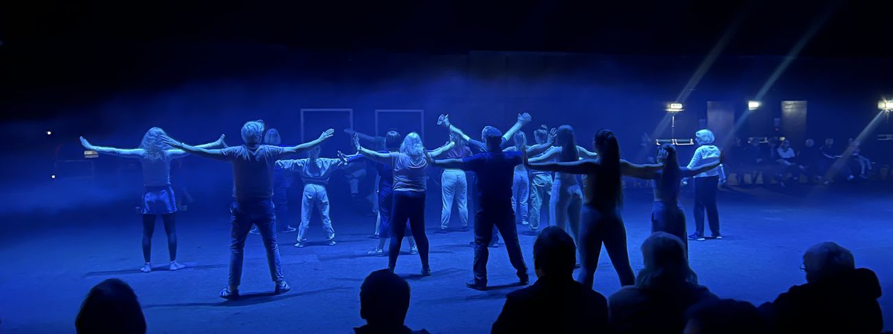 Dance troupe performing under blue stage lighting