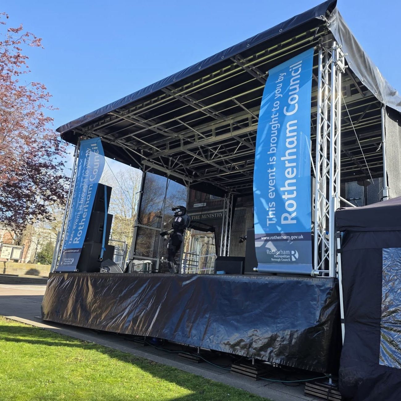 Covered modular stage with ground-stacked PA and event banners at Roots Festival