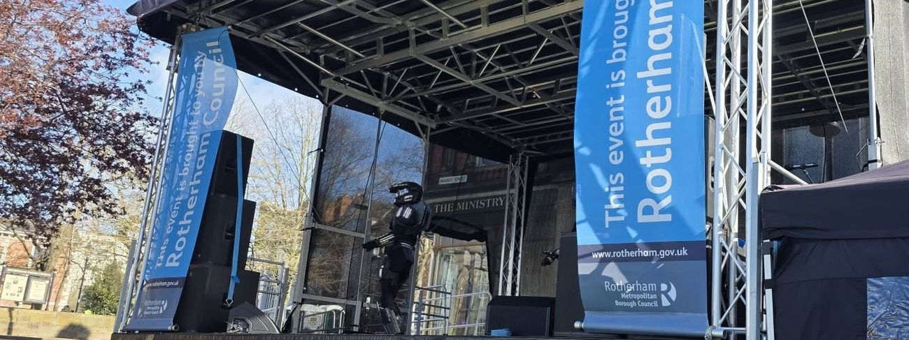 Covered modular stage with PA and council banners at Roots Festival in Rotherham